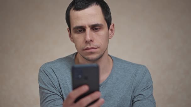 Здивований чоловік дивиться на мобільний телефон — стокове відео