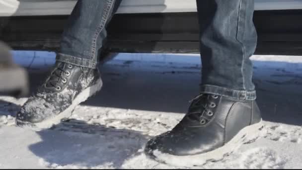 Mann schüttelt den Schnee von Stiefeln ab, bevor er ins Auto steigt — Stockvideo