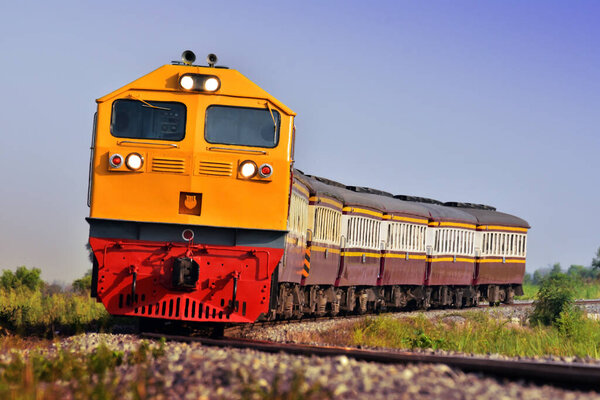 Passenger train by diesel locomotive passes the curve on railway in Thailand