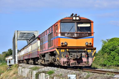 Passenger train by diesel locomotive passes the bridge on railway in Thailand