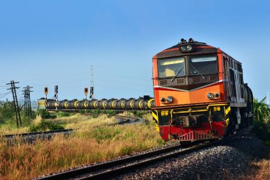 Tanker-freight train by diesel locomotive passes the curve on railway in Thailand