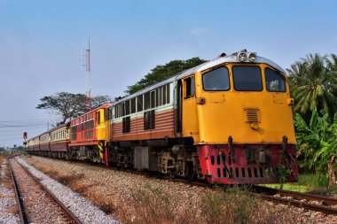 Passenger train by double headed diesel locomotives on the railway in Thailand