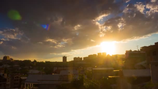 Тимелапс драматичного заходу сонця над міським пейзажем з пухнастими хмарами, дощем і золотим сонцем на блакитному небі — стокове відео