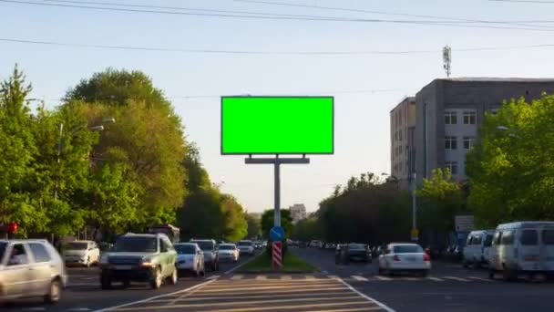 Una cartelera con una pantalla verde en un fondo de tráfico de la ciudad con coches, personas caminando, árboles, cielo azul. En Armenia ciudad Ereván. La cámara se aleja — Vídeos de Stock