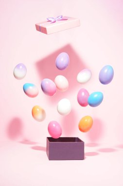 Pembe arka planda pembe kapaklı menekşe kutusundan renkli yumurtalar çıkan yaratıcı Paskalya konsepti. Asgari Paskalya Tatili fikri.