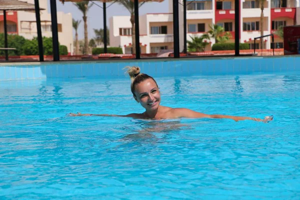 Νεαρή γυναίκα στην πισίνα του ξενοδοχείου, σε καλή διάθεση, με ένα χαμόγελο στο πρόσωπό της. — Φωτογραφία Αρχείου