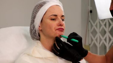 Güzellik salonundaki yüz güzelliği enjeksiyonundan önce hastaya işaret koymak..