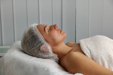 Hasta, güzellik uzmanındaki ameliyattan önce kanepede yatıyor.