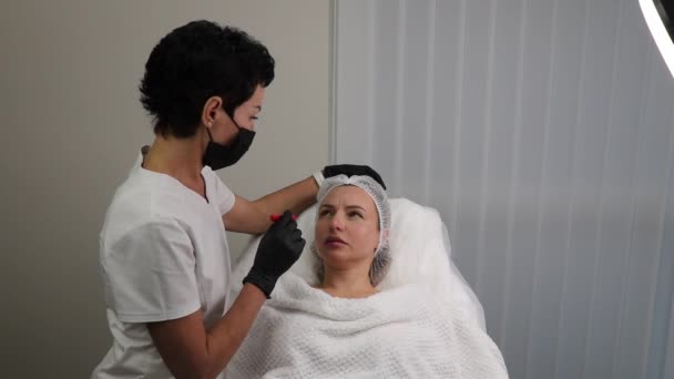 Marking with a marker before the facial beauty injection procedure — Stockvideo