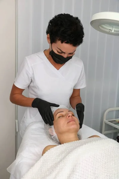 The beautician examines the patient before the facial treatment. — Stockfoto