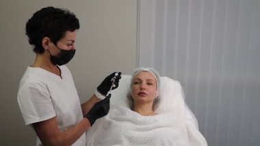 The beautician draws the anti-wrinkle filler from the container into the syringe.