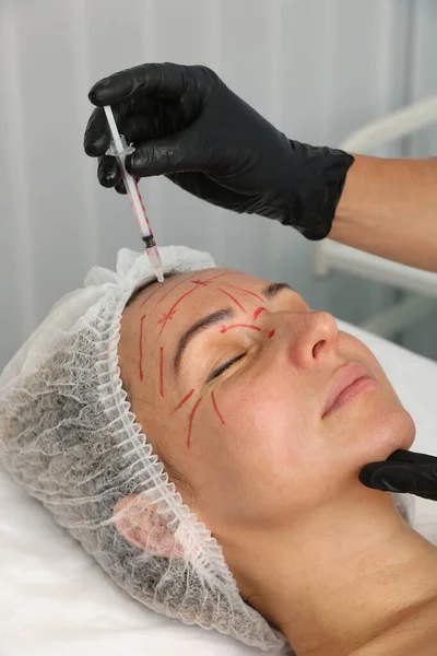 Beautician gives wrinkle injections to a middle-aged woman. — Stock Photo, Image