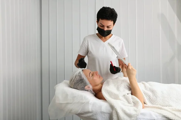 Beautician examines the face of the patient looking in the mirror — Photo