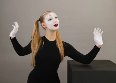 Sirk kızı, pandomimci kız, siyah küpün yanında. Hayranlık duygusuyla, gri bir arkaplanda.