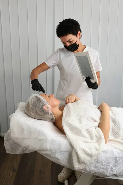 Esthéticien Examine Visage Patient Regardant Dans Miroir Après Une Procédure — Photo