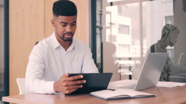 Ofiste dijital tablet ve laptop kullanan bir işadamı — Stok video