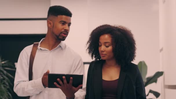 A businesswoman and a businessman using a digital tablet walking into the workplace — Stock video