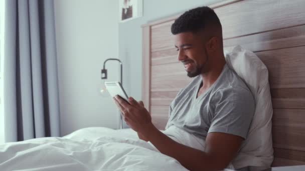 Rekaman seorang pria menggunakan tablet saat di tempat tidur — Stok Video