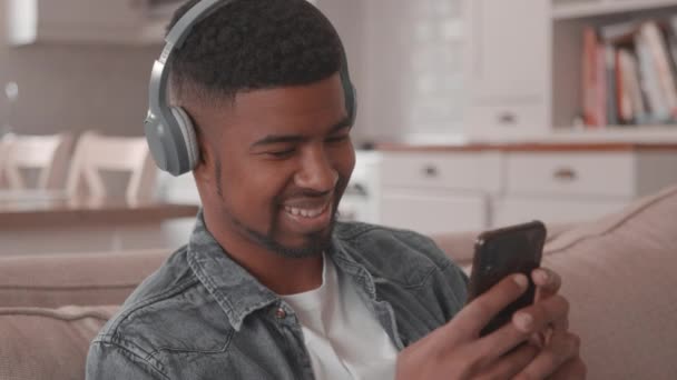 Πλάνα ενός άνδρα που ακούει μουσική ενώ χρησιμοποιεί ένα smartphone — Αρχείο Βίντεο