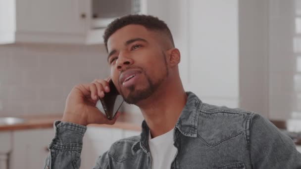 Een man die in de keuken zit tijdens een telefoongesprek — Stockvideo
