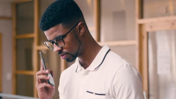 Ein Geschäftsmann, der im Büro mit einem Handy telefoniert — Stockvideo