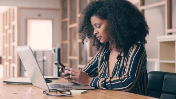 Business woman using a cellphone sitting in her office — Stockvideo