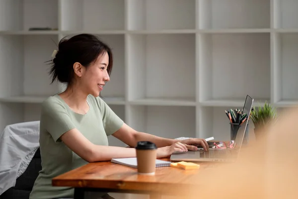 与坐在办公桌上的年轻的亚洲女人手拉手，在笔记本电脑上交流笔记。在咖啡店使用平板电脑的女性. — 图库照片