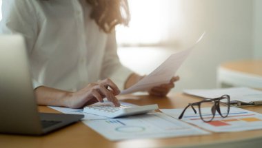 İş kadını veya muhasebeci Finansal Yönetici Araştırma Süreci muhasebe hesaplama ile hesaplama pazar grafik veri bilgi değerlendirmesi için hesap makinesi ile ofisteki masada hesaplama.