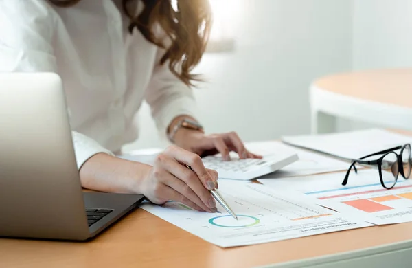 Sluiten van zakenvrouw of accountant hand holding pen werken aan rekenmachine voor de berekening van bedrijfsgegevens, boekhoudkundige document en laptop computer op kantoor, business concept. — Stockfoto