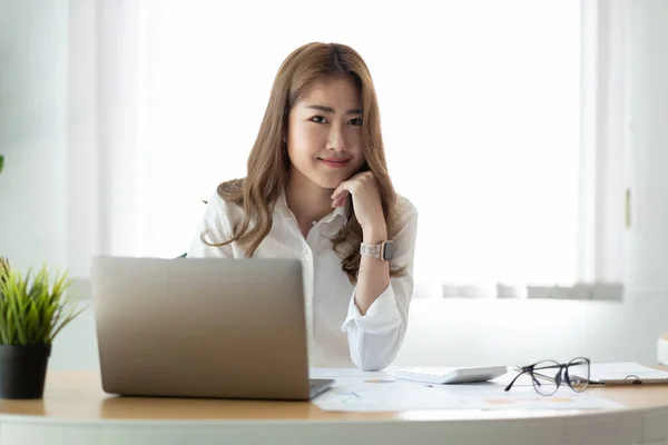 금융 보고서를 작성하는 데 계산기를 사용하는 경영 아시아 여성. 그녀는 노트북 컴퓨터와 함께 일하고 있습니다. — 스톡 사진