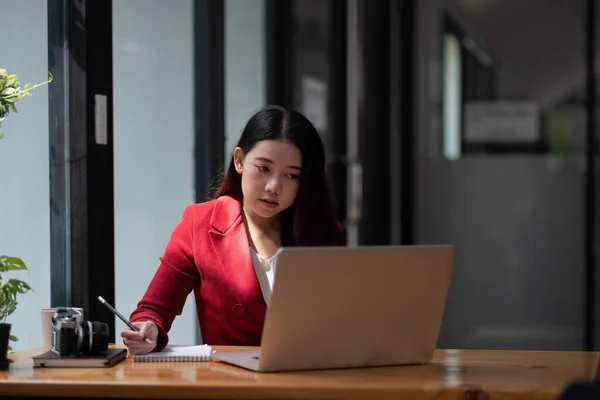 Asiatische Geschäftsfrau arbeitet am Laptop und notiert im Büro. — Stockfoto