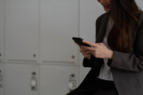 Mulher trabalhadora alegre usando telefone celular sorrindo com prazer enquanto lê uma mensagem de texto no escritório — Fotografia de Stock