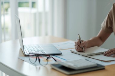 Mali denetim ve hesaplama yapan muhasebeci kadın yıllık mali rapor bilanço tablosu beyanı, kağıt kontrol belgesi üzerinde notlar tutarak finansman yapıyor.