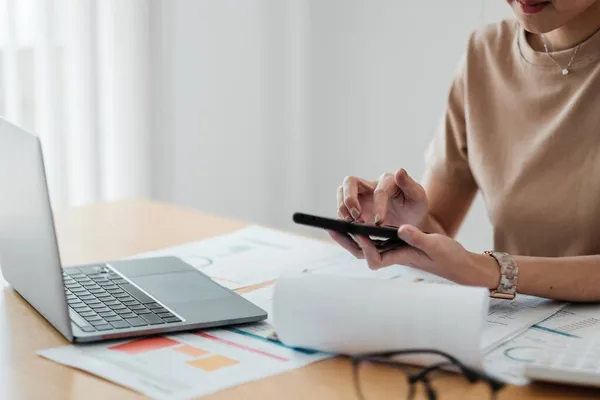 Primer plano de trabajo femenino joven con papeles financieros en casa contar con calculadora antes de pagar los recibos de impuestos en línea por teléfono — Foto de Stock