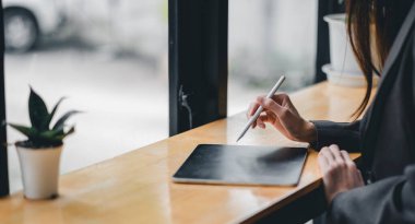 İş kadını el yazısı, kafeteryadaki dijital tablet üzerinde stilus kalemle çalışıyor.
