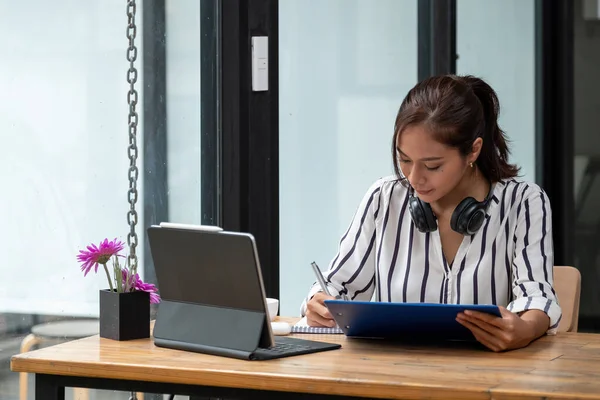 Not defterine not alan Asyalı kadın evde e-öğrenim için dizüstü bilgisayar kullanıyor. — Stok fotoğraf
