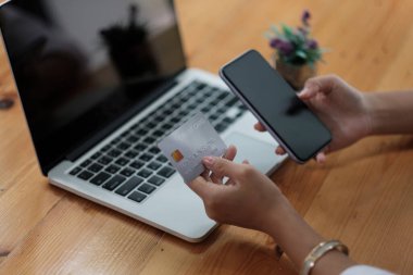 Kredi kartı tutan ve evde akıllı telefon kullanan bir kadın, işadamı çevrimiçi alışveriş, e-ticaret, internet bankacılığı, harcama, ev kavramından çalışma