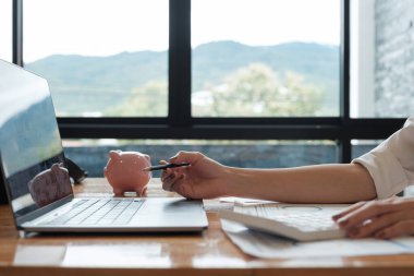 Masrafları ve muhasebe kavramını hesaplamak için ofiste hesap makinesiyle finans hakkında çalışan bir muhasebeciyi kapat