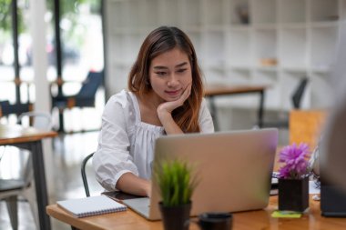 Kafede dizüstü bilgisayar kullanan mutlu Asyalı kadın.