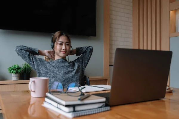 헤드폰을 끼고, 노트북에서 교육용 웹 사이트를 보는 것을 즐기는 행복 한 이시아 여성 — 스톡 사진