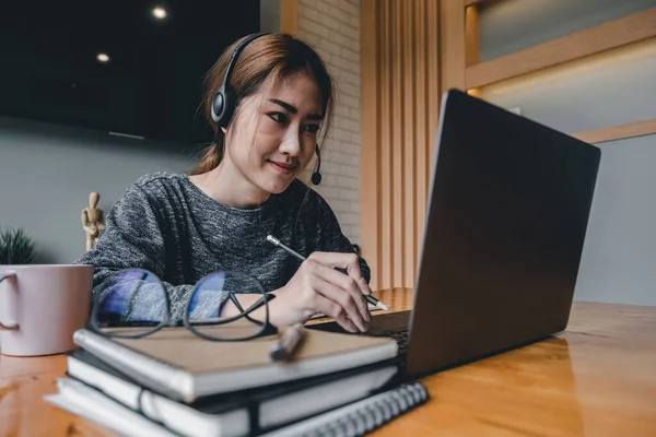 헤드폰을 끼고, 노트북에서 교육용 웹 사이트를 보는 것을 즐기는 행복 한 이시아 여성 — 스톡 사진
