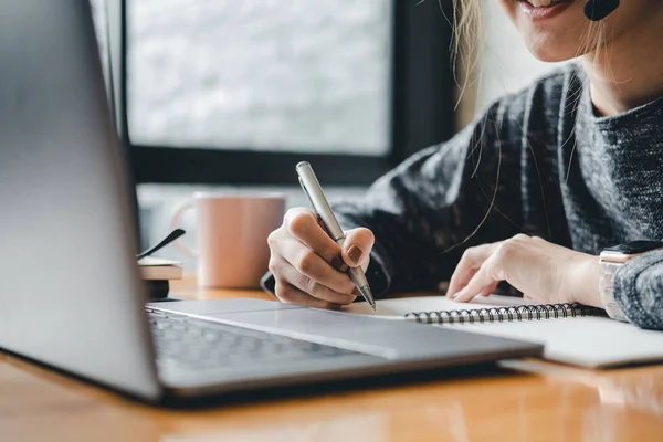 Primer plano foto de la mujer escribiendo haciendo lista tomando notas en bloc de notas trabajando o aprendiendo en el ordenador portátil en el interior curso de educación o formación, seminario, educación concepto en línea —  Fotos de Stock