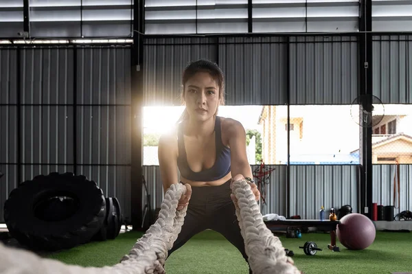 Atractivo fuerte asiática fitness mujer haciendo batalla cuerdas ejercicio en el gimnasio. entrenamiento con pesas sesión de ejercicio — Foto de Stock