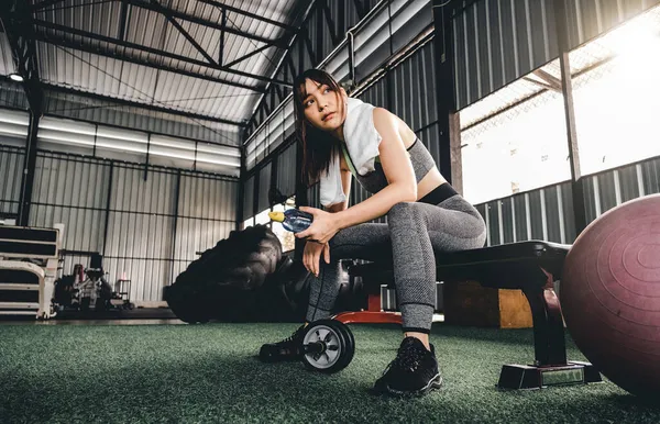 Atractiva mujer fitness sentada en una silla y descansando después del entrenamiento en el gimnasio. Mujer tomar un descanso después de cardio duro — Foto de Stock