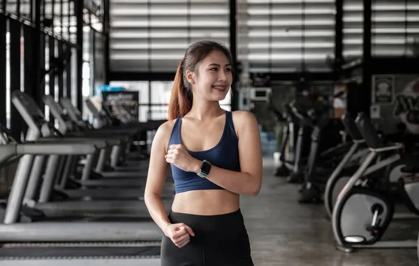 Retrato de mujer de fitness asiática hermosa y segura de pie después del ejercicio en el gimnasio. Concepto de entrenamiento de niña feliz delgada y saludable — Foto de Stock