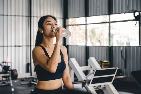 Азиатская молодая женщина питьевой воды после тренировки в тренажерном зале, исцеления и спортивной концепции. — стоковое фото