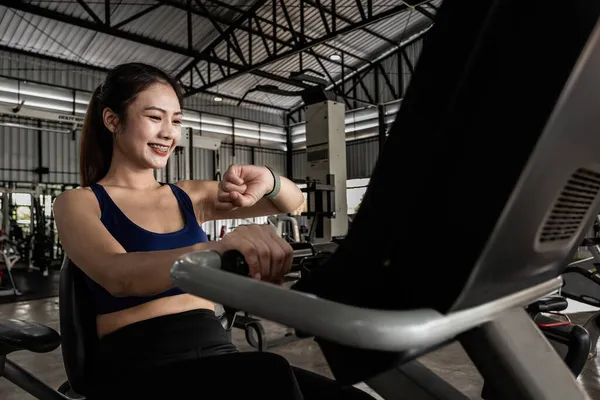 Entrenamiento de mujer joven en el gimnasio estilo de vida saludable, Mujer está utilizando reloj inteligente durante su entrenamiento con spinning o cyclo — Foto de Stock