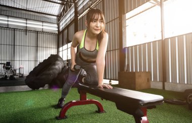 Çekici bir Asyalı kadın spor salonunda bir dambılı kaldırmaya konsantre olur. ağırlık çalışması
