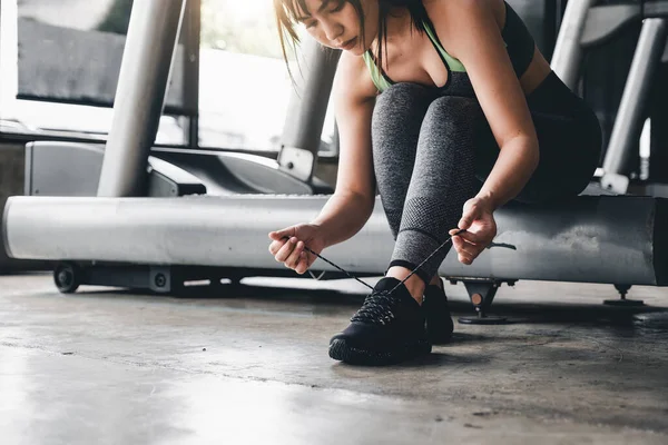 Primer plano de mujer joven asiática cordones zapatos deportivos antes de hacer ejercicio en el gimnasio. — Foto de Stock