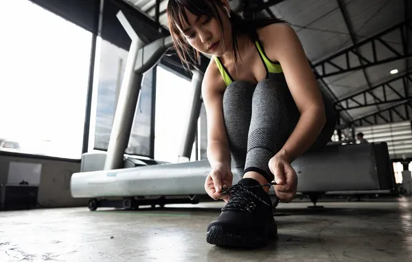 Primer plano de mujer joven asiática cordones zapatos deportivos antes de hacer ejercicio en el gimnasio. — Foto de Stock